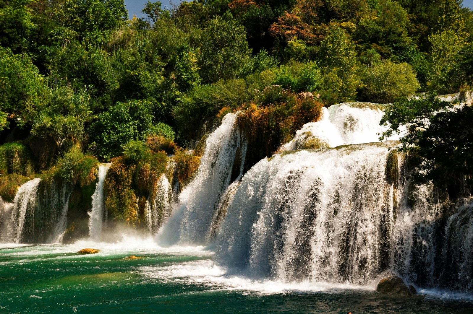 Beautiful cascading waterfalls surrounded by lush greenery in a serene Croatian forest setting.